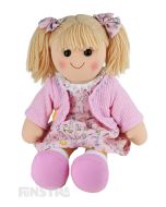 Willow is an adorable doll with a soft cloth body and blonde hair tied in pigtails with bows and wears a pastel pink whimsical printed dress and cardigan.