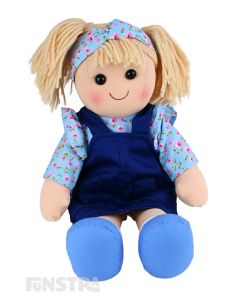Carrie is a beautiful doll with a soft cloth body and blonde hair tied back in pigtails and wears a blue pinafore dress over a floral top and a matching headband.